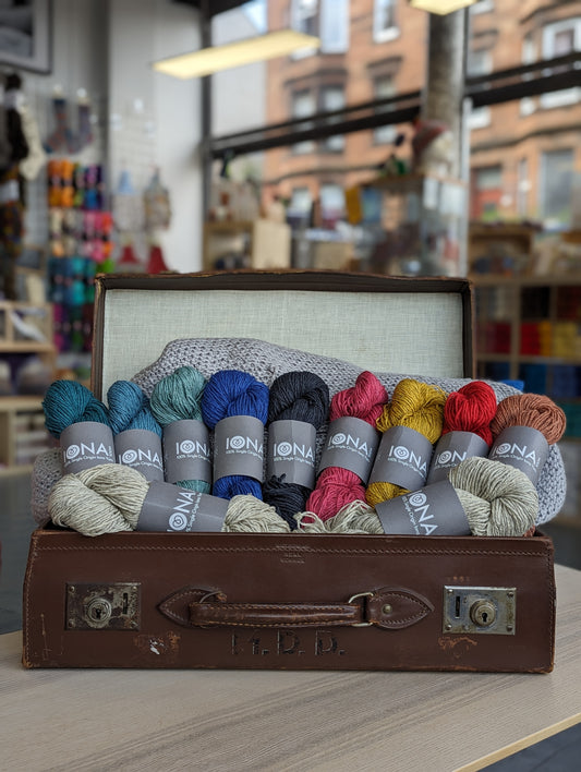 The beautiful IW6 collection in the Aran Weight. Placed in an old leather briefcase with the shop in the background. 