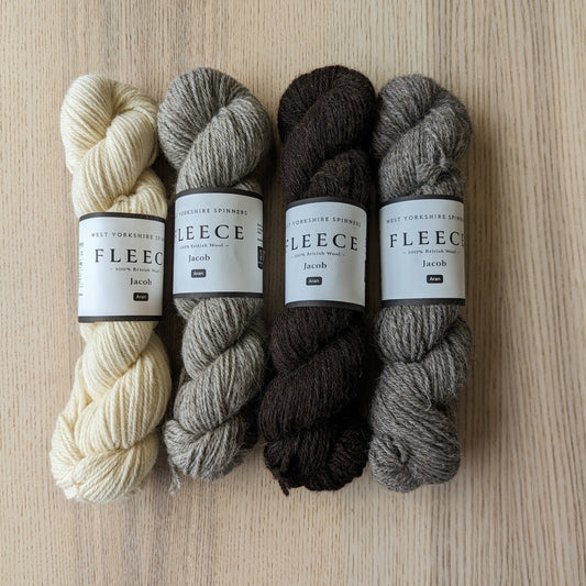 The four Jacob's fleece aran lain out on a wooden backdrop. Left to Right - Ecru, Light Grey, Brown/Black and Dark Grey