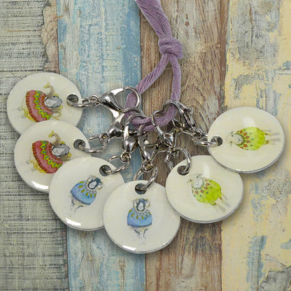 6 Sheep in Sweaters round stitch markers attached to a piece of string on a wood texture background.