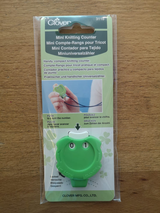 Mini knitting counter. Green plastic with a cord to hang it around your neck and a push button to change the number.